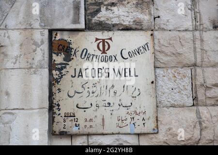 A hand painted information board in English & Arabic, outside the Jacob's Well. Nablus. Palestine Stock Photo
