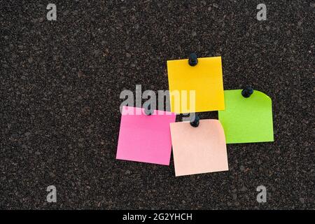 Colorful note papers on a brown cork bulletin board. Close up. Stock Photo