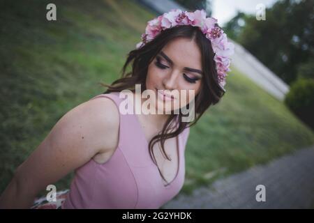 A portrait of an attractive Caucasian female wearing a floral headband posing in a park Stock Photo