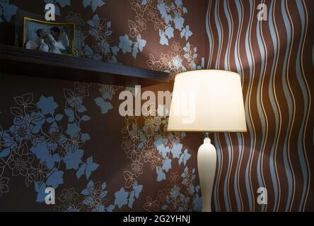 Table lamp dimly shines on the table in the bedroom. Stock Photo