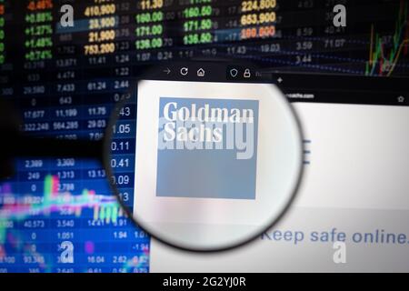 Goldman Sachs company logo on a website with blurry stock market developments in the background, seen on a computer screen through a magnifying glass Stock Photo