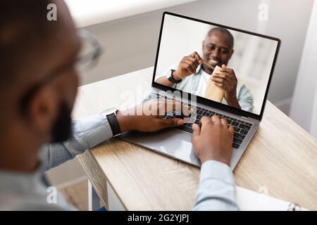 Young man watching online DIY class, participating in woodworking workshop, using laptop at home Stock Photo