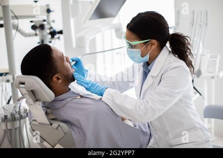 Portrait Of Black Male Patient Getting Teeth Treatment With Dentist At Clinic Stock Photo