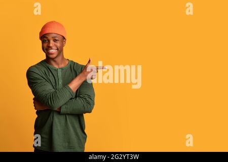 Look At This. Positive Young Black Man Pointing Aside At Copy Space Stock Photo