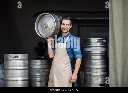 Attractive confident strong man working at plant. Owner of brewery, employee at storage Stock Photo