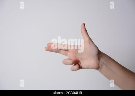 Girl's hand making shooting gun, gesture. hand pistol gesture on isolated white background. Girl hand pointing with two fingers. Stock Photo