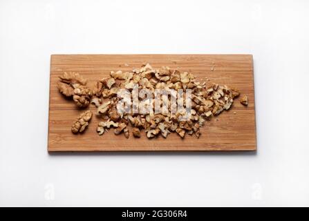 Chopped walnuts on a wooden cutting board isolated on white background. Directly above. Stock Photo