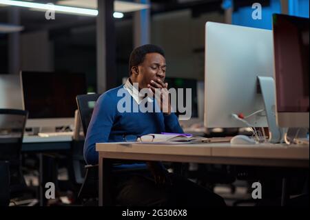 Tired young man works in night office Stock Photo