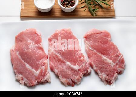 Veal escalopes with spices on a white plate. Directly above. Stock Photo
