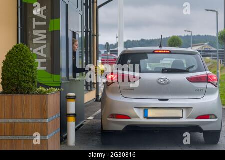 Partille, Sweden. June 11 2021: McDonald's drive-through or drive-thru customer being handed over fast food order Stock Photo
