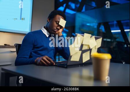 Stressed manager works on laptop, night office Stock Photo