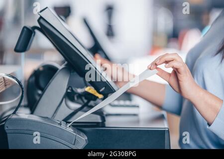 Saleswoman printing invoice or receipt for a customer in the shopping center, POS system Stock Photo