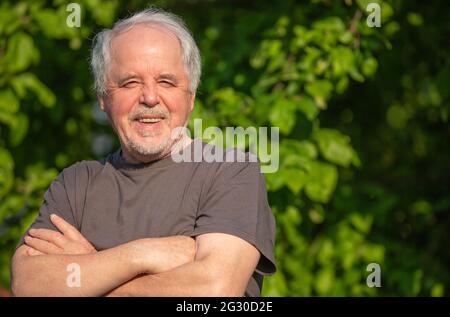 Portrait of smilling senior man or pensioner at his huge garden during lovely summer day, lifestyle concept Stock Photo