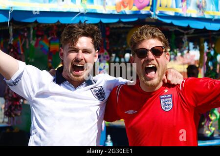 Hastings, East Sussex, UK. 13 June, 2021. England fans drink outside in the sunny weather on the Hastings pier that has provided a large screen a beer bar. Two England fans celebrate England's victory. Photo Credit: Paul Lawrenson /Alamy Live News Stock Photo