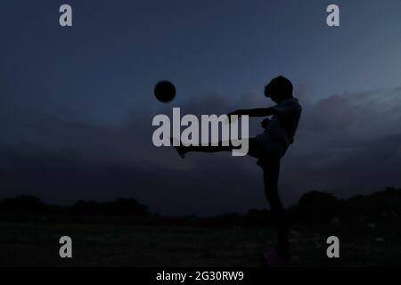 Chennai, Tamil Nadu, India. 13th June, 2021. As the dark clouds loom over the skies, kids seen playing football at a deserted ground in Chennai. Credit: Sri Loganathan/ZUMA Wire/Ģ����ý Live News Stock Photo