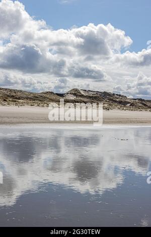 Water on the beach with mirror reflection of white clouds and dunes in the background, day with a blue sky and abundant clouds in Hargen aan Zee, Nort Stock Photo