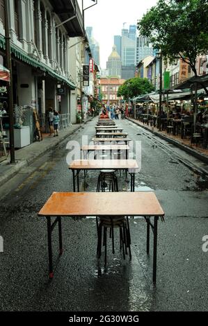 Long line of tables stretching down the centre of a narrow street, between rows of restaurants. Chinatown, Singapore Stock Photo