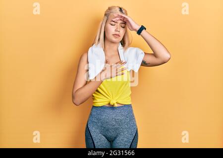 Beautiful blonde sports woman wearing workout outfit touching forehead for illness and fever, flu and cold, virus sick Stock Photo