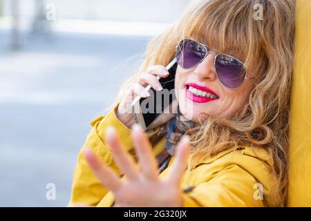 portrait of senior adult woman talking on the phone in the street Stock Photo