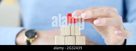 Woman building pyramid from wooden cubes closeup Stock Photo