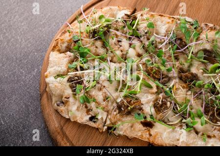 Italian pinsa romana with french escargot grape snails on dark background. Pinsa with snail, cheese, microgreen. Italian gourmet cuisine. Stock Photo