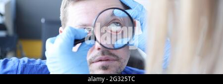 Doctor examining patients eye with magnifying glass closeup Stock Photo