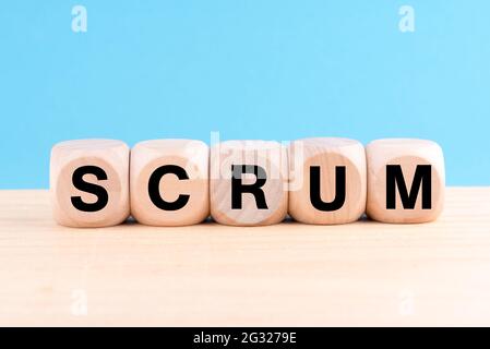 A closeup shot of 5 wooden blocks on the table with the word scrum isolated on a blue background Stock Photo