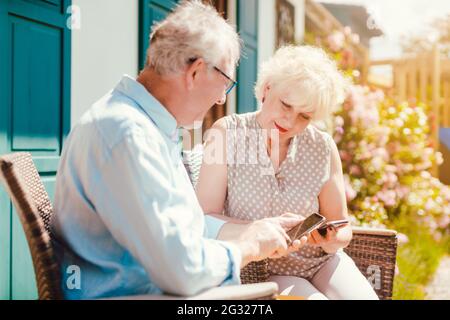 Senior couple looking at their phone in the garden Stock Photo