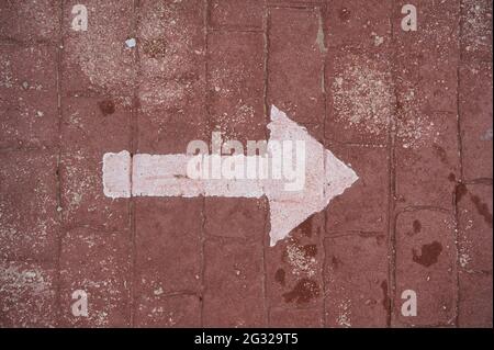 white right arrow painted on red street. view Stock Photo
