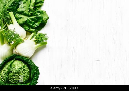 Fresh Florence fennel bulbs and savoy cabbage on white wooden background. Raw organic spring vegetables top view. Genuine healthy eating. Stock Photo