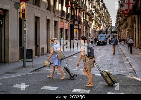 Barcelona, Spain. 13th June, 2021. Tourists walk along Las Ramblas with their suitcases. With 50% of the citizens of Catalonia vaccinated with the first dose, tourism begins to be seen in the streets of Barcelona, especially in the historic center of the city. Bars, shops, restaurants, recreational activities for tourism, all are activated with the arrival of visitors. Credit: SOPA Images Limited/Alamy Live News Stock Photo