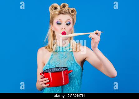 Woman with cooking utensils in kitchen. Retro style housewife with saucepan and spoon. Cuisine, culinary, household concept. Stock Photo