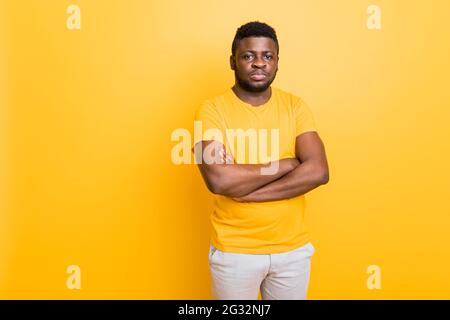 Portrait of handsome confident millennial African American male, handsome young male wearing yellow t-shirt having arms crossed, serious guy, student Stock Photo