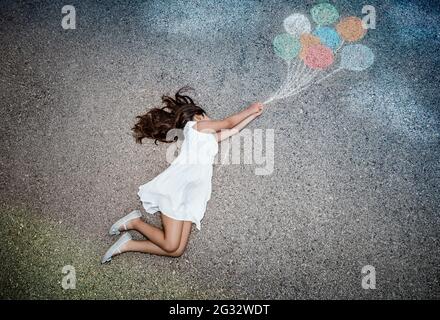 Conceptual Image of Freedom Joy and Happiness. Little Girl Flying Away on Colorful Balloons. Enjoying Life. Dreamy Childhood. Creative Imagination. Stock Photo