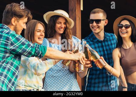 Group of young friends having fun at a party outdoors, drinking cold drinks, making barbecue and grilled vegetables, enjoying hot summer days, Stock Photo