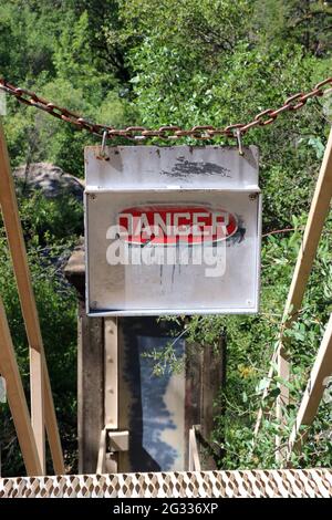 Weathered red and white danger sign with a metal chain at the top of stairs leading to an old pumping station, Rainbow Pool, Groveland, CA. Stock Photo