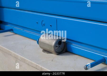 Close-up of a padlock on the lock of a blue blind of a shop at street level Stock Photo