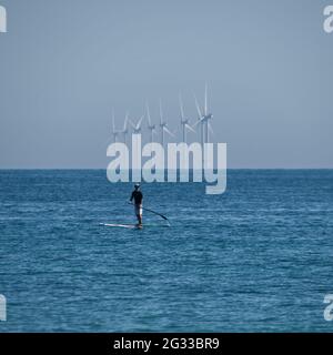 Paddle board by wind turbines Stock Photo