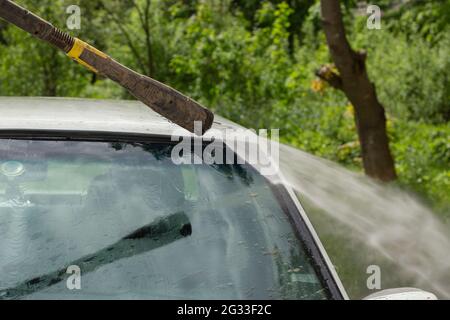 Washing the windshield from dirt. The car is washed by the pressure of the walls. Caring for vehicles after a muddy road. Stock Photo