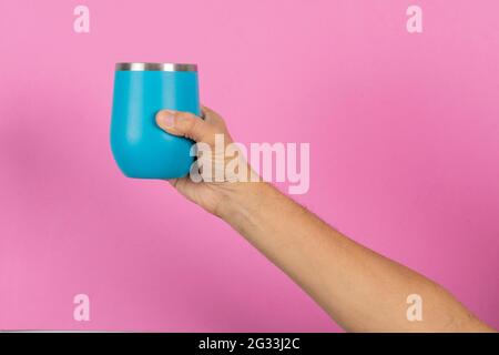 male hand holding a blue mug on pink background Stock Photo