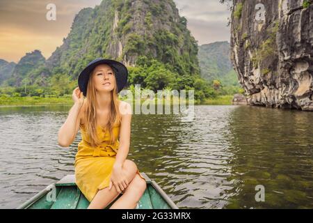 Woman tourist in boat on the lake Tam Coc, Ninh Binh, Viet nam. It's is UNESCO World Heritage Site, renowned for its boat cave tours. It's Halong Bay Stock Photo