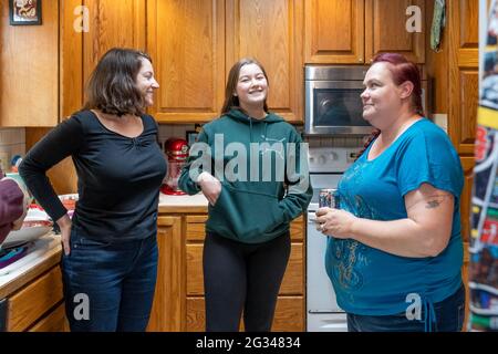 Mother, 15 year old daughter and sister-in-law having a friendly chat in a kitchen.  (MR) Stock Photo