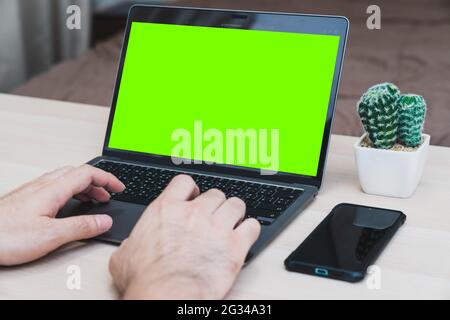 Young businessman working on laptop in home, rear view green screen of business man hands busy using laptop at office desk, typing on computer sitting Stock Photo