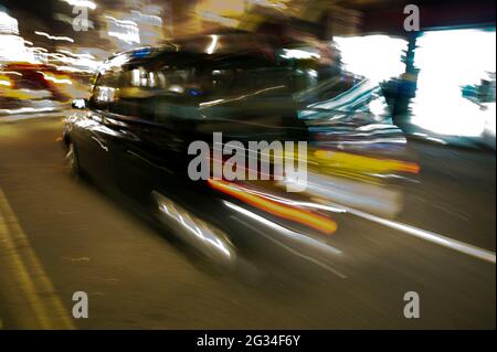 Blurred image of London black cab driving on a street at night Stock Photo