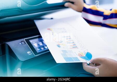 Office worker print paper on multifunction laser printer. Copy, print, scan, and fax machine in office. Modern print technology.  Photocopy machine. Stock Photo