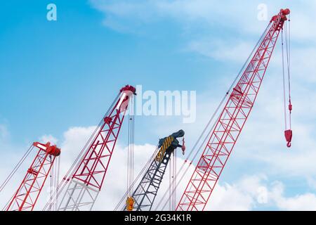 Crawler crane against blue sky and white clouds. Real estate industry. Red crawler crane use reel lift up equipment in construction site. Crane. Stock Photo