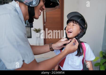 father taking his daughter to school by motorcycle in the morning Stock Photo