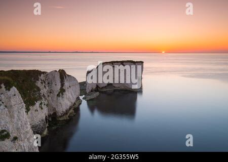 Old Harry Rocks, Swanage, Dorset, UK.  14th June 2021.  UK Weather.  The sea is like a millpond at sunrise at Old Harry Rocks near Swanage in Dorset on a warm clear summer morning.   Picture Credit: Graham Hunt/Alamy Live News Stock Photo