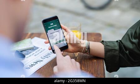 Unrecognizable couple travelers with smartphone looking for accomodation in city on holiday. Stock Photo