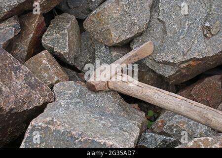 Heap of granite stones. Old pickaxe lies on the stones. Stock Photo